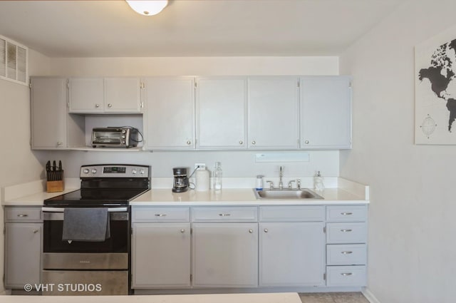 kitchen with visible vents, a toaster, light countertops, electric range, and a sink