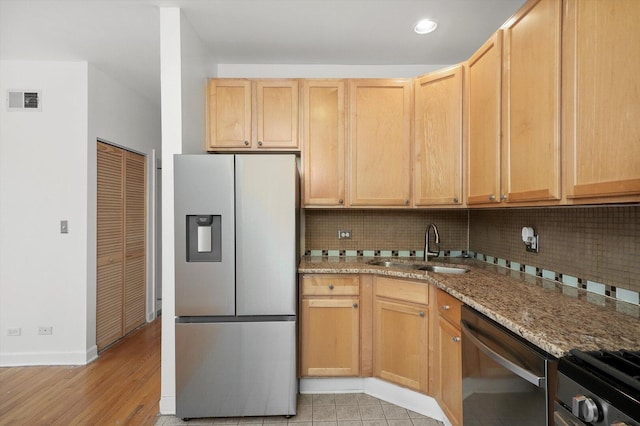 kitchen featuring tasteful backsplash, visible vents, light stone countertops, appliances with stainless steel finishes, and a sink