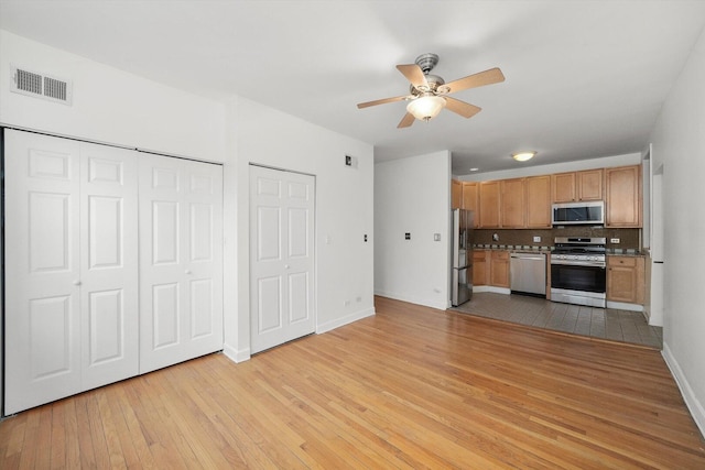 kitchen with tasteful backsplash, visible vents, light wood-type flooring, stainless steel appliances, and a ceiling fan