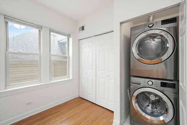 laundry room featuring visible vents, baseboards, laundry area, light wood-style flooring, and stacked washer / drying machine