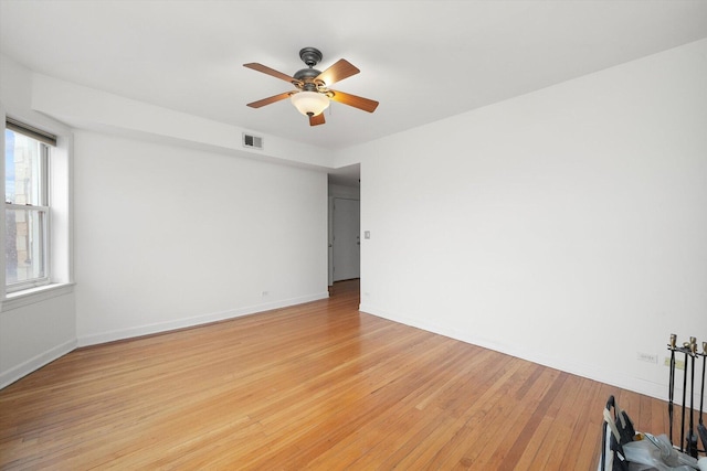 unfurnished room with visible vents, light wood-style flooring, a ceiling fan, and baseboards