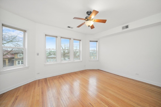 unfurnished room featuring visible vents, plenty of natural light, and light wood-style floors