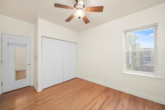 unfurnished bedroom with a closet, baseboards, light wood-style floors, and a ceiling fan