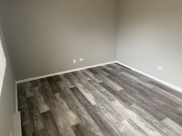 empty room featuring dark wood-type flooring and baseboards