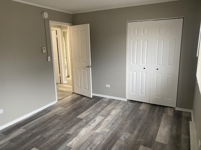 unfurnished bedroom featuring crown molding, a closet, dark wood-style floors, and baseboards