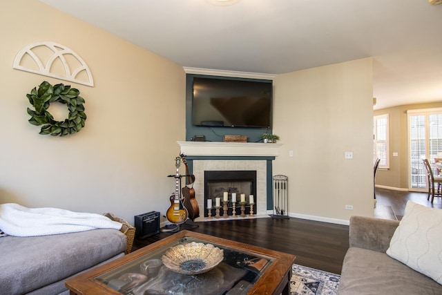 living area featuring baseboards, a tiled fireplace, and wood finished floors