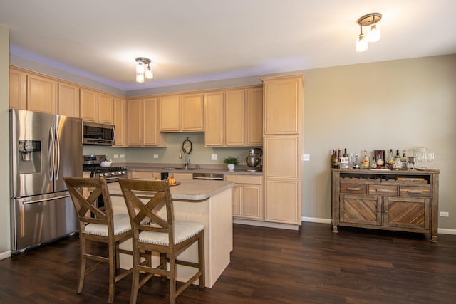 kitchen with dark wood-style floors, stainless steel appliances, light brown cabinetry, and a kitchen island