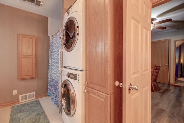 laundry room featuring laundry area, baseboards, visible vents, a ceiling fan, and stacked washer / dryer