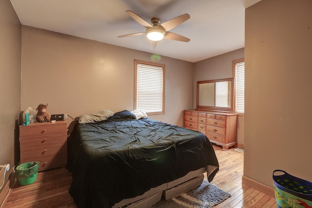 bedroom with light wood-style flooring, multiple windows, baseboards, and a ceiling fan