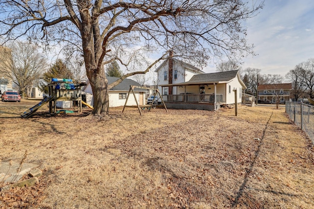 view of yard featuring a playground, fence, and a wooden deck