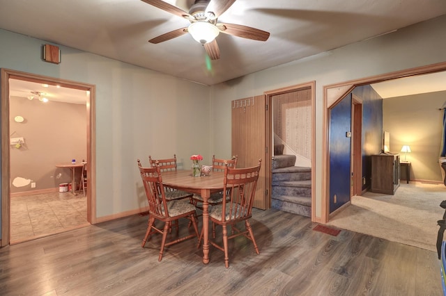 dining room with stairs, ceiling fan, wood finished floors, and baseboards