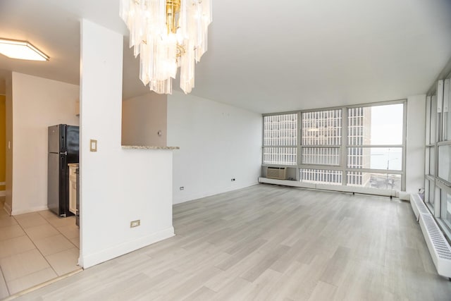 unfurnished living room featuring light wood-type flooring, floor to ceiling windows, and baseboards