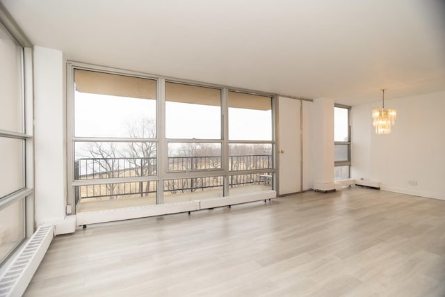 unfurnished room with an inviting chandelier, light wood-style flooring, floor to ceiling windows, and baseboards