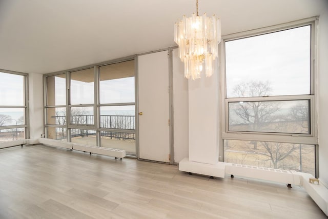 interior space featuring a chandelier, expansive windows, and light wood-style flooring