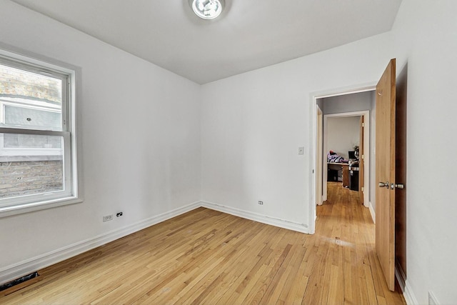 spare room featuring light wood finished floors and baseboards