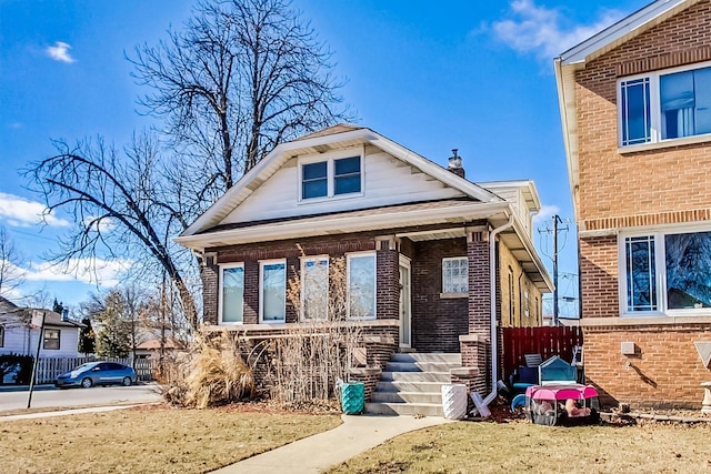 bungalow-style house with covered porch, brick siding, and fence