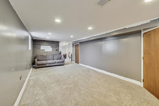 finished basement with carpet, recessed lighting, visible vents, an accent wall, and wood walls