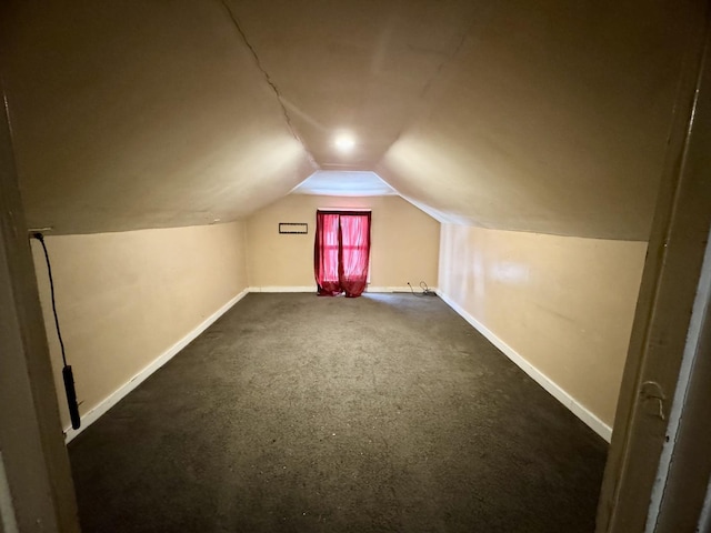 bonus room featuring lofted ceiling, dark carpet, and baseboards