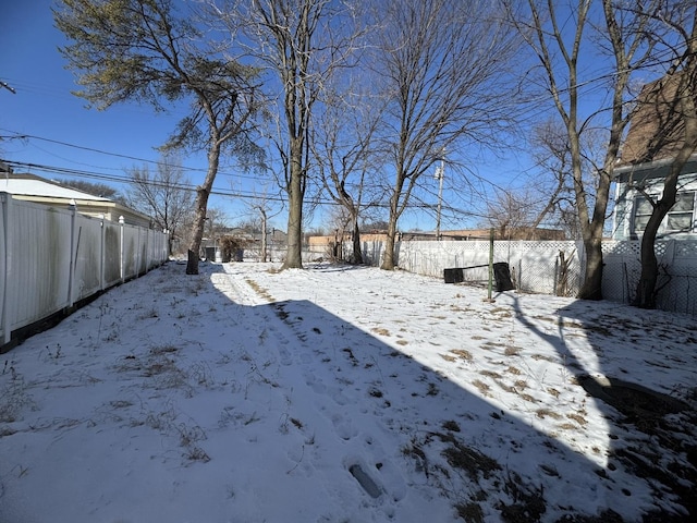 snowy yard featuring a fenced backyard