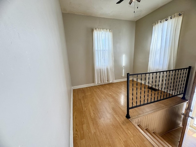 interior space with ceiling fan, light wood finished floors, and baseboards