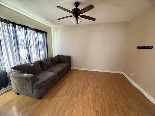 living room with light wood-type flooring, baseboards, and a ceiling fan