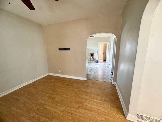 spare room featuring visible vents, arched walkways, ceiling fan, and wood finished floors