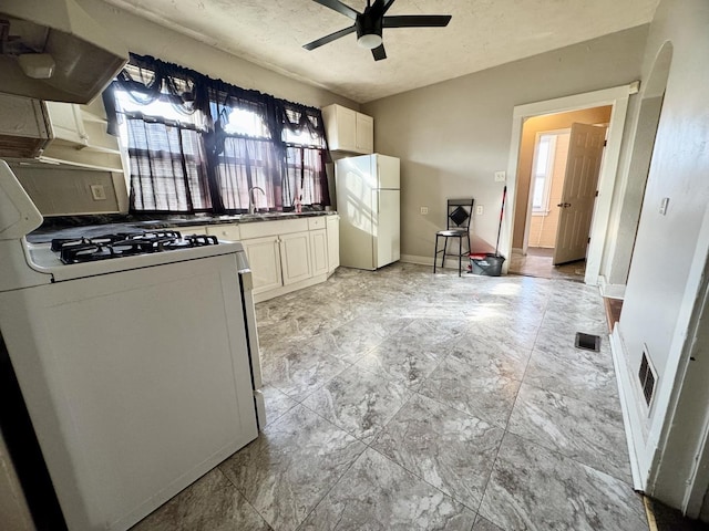 kitchen with white appliances, a ceiling fan, white cabinets, visible vents, and range hood