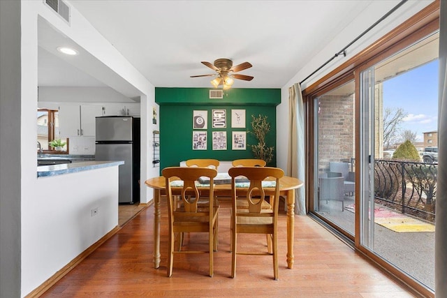 dining space with light wood-style flooring, visible vents, and ceiling fan