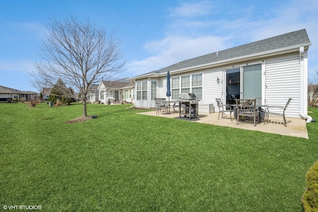 rear view of property featuring a patio, a lawn, and roof with shingles