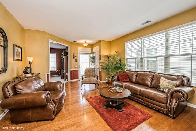 living area with light wood-style floors, visible vents, and baseboards