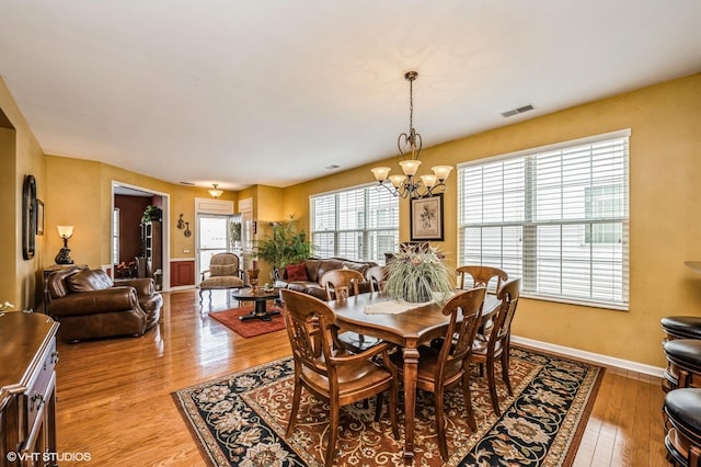 dining space with a chandelier, visible vents, light wood-style flooring, and baseboards