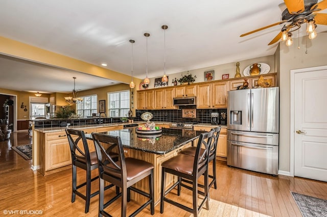 kitchen featuring a peninsula, light wood finished floors, plenty of natural light, and appliances with stainless steel finishes