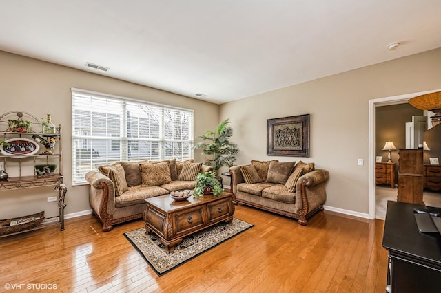 living room featuring light wood finished floors, visible vents, and baseboards