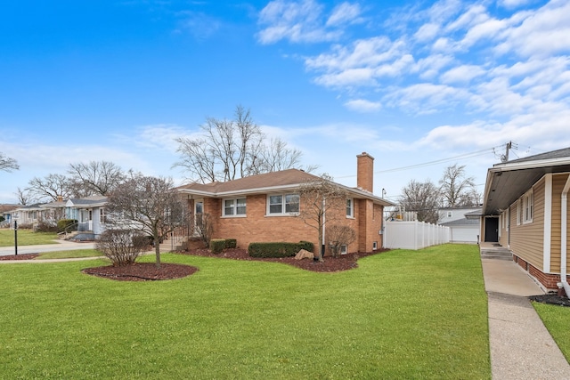 view of home's exterior with brick siding, fence, a chimney, and a lawn