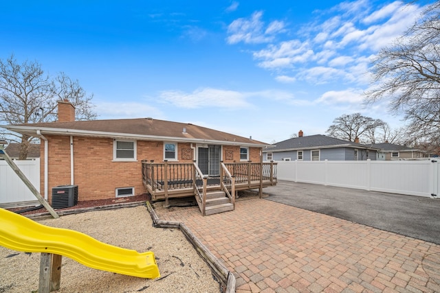 rear view of house featuring brick siding, a playground, a chimney, central air condition unit, and a patio area