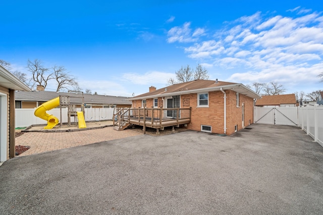 rear view of property with a fenced backyard, a chimney, a gate, a playground, and brick siding