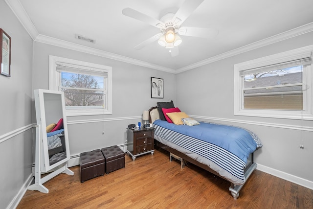 bedroom with multiple windows, crown molding, visible vents, and wood finished floors