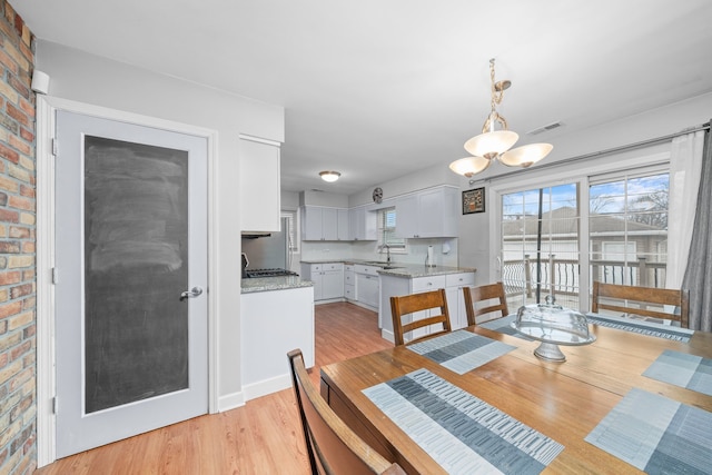 dining area featuring light wood finished floors, visible vents, and a notable chandelier