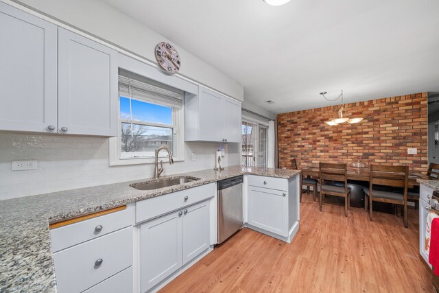 kitchen featuring a peninsula, a sink, white cabinetry, light wood-style floors, and stainless steel dishwasher