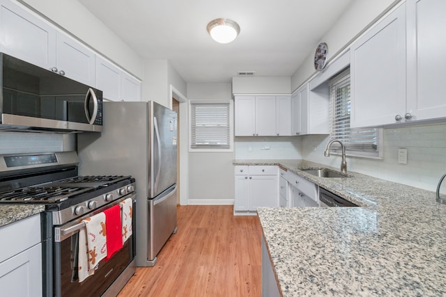 kitchen with stainless steel appliances, light wood-style floors, white cabinets, and a sink