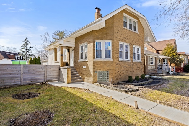 exterior space featuring a yard, fence, brick siding, and a chimney