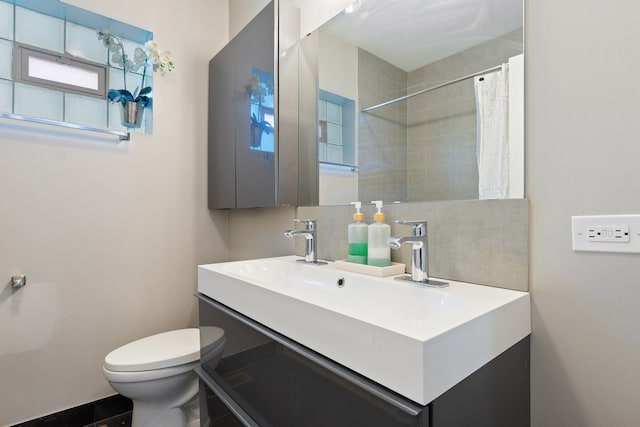 bathroom with decorative backsplash, curtained shower, toilet, and vanity