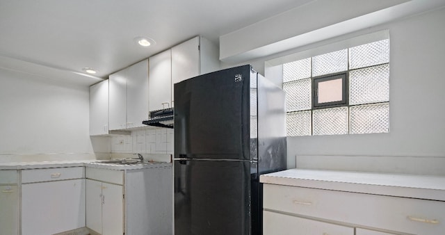 kitchen with a sink, white cabinets, light countertops, and freestanding refrigerator