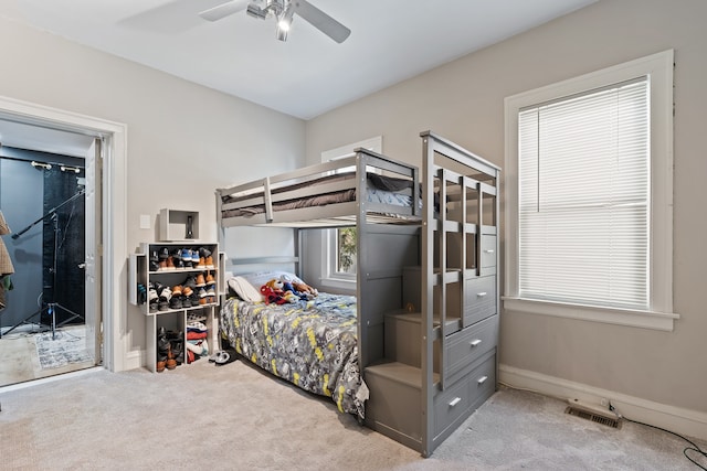 carpeted bedroom with visible vents, multiple windows, baseboards, and ceiling fan