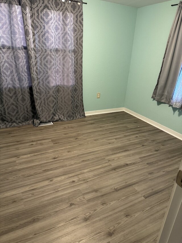 unfurnished room with baseboards and wood finished floors