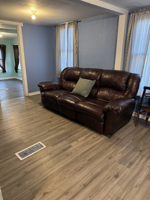 living room featuring a textured ceiling, wood finished floors, and visible vents