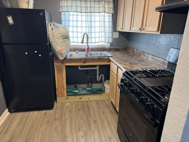 kitchen with a textured wall, a sink, under cabinet range hood, and black appliances