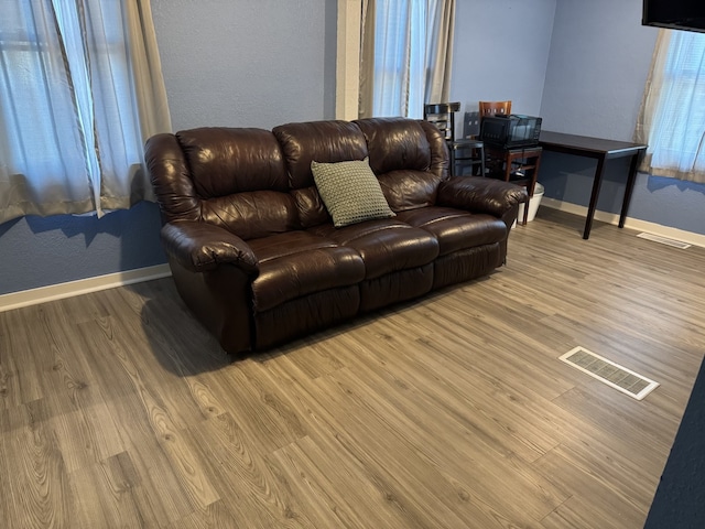 living room with light wood-style floors, baseboards, and visible vents