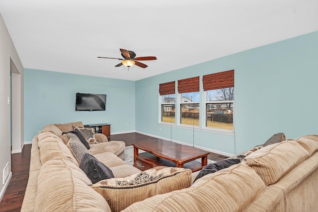 living area with a ceiling fan, dark wood-style flooring, and baseboards