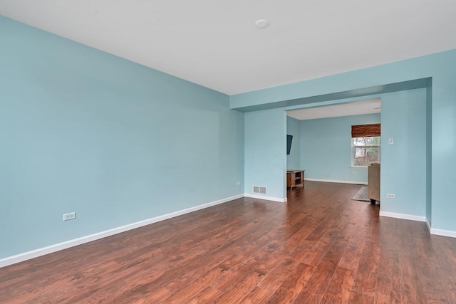 spare room featuring baseboards, visible vents, and dark wood-style flooring